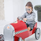 Enfant pédalant un porteur avec un chapeau et des lunettes de pilote